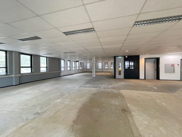 Leeg kantoorpand aan de Rivium 4e Straat met systeemplafond, grote ramen en een lift.